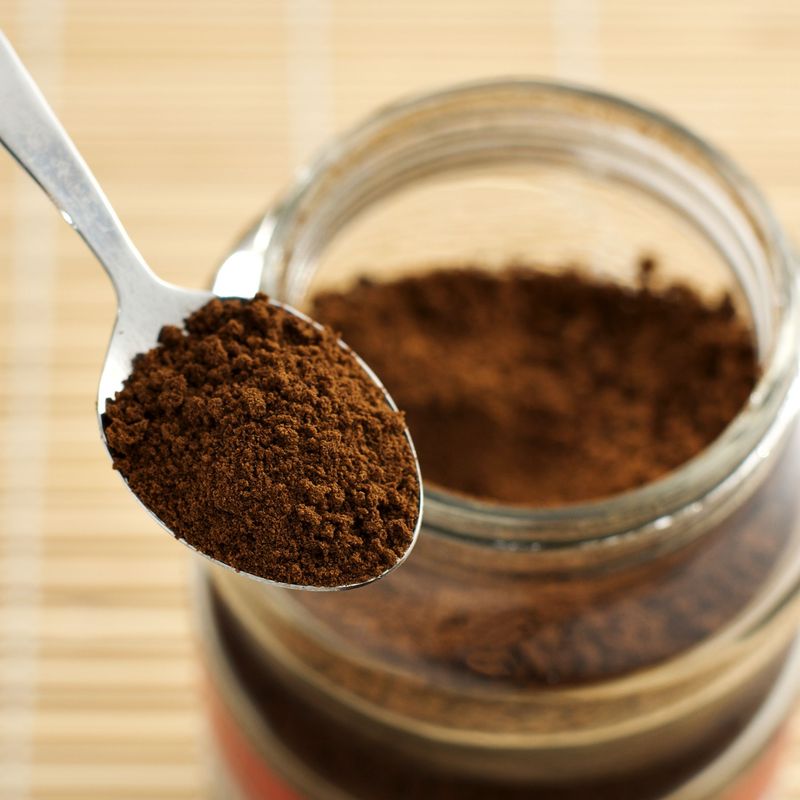 a teaspoon of instant coffee with an open jar in the background