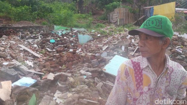 Seorang warga berdiri di depan reruntuhan bangunan