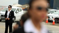 Paspampres wanita itu tampil elegan mengenakan setelan jas warna hitam.