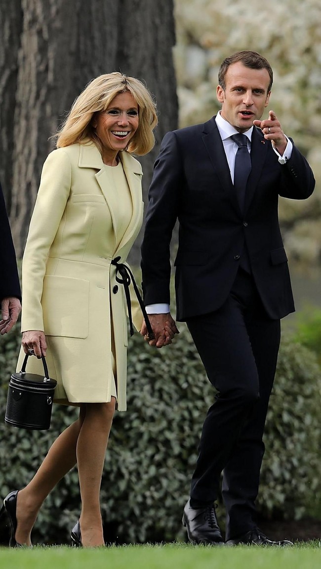 Brigitte Macron di lain sisi, memilih coat dan dress berwarna kuning pucat juga dari Louis Vuitton. Kedua Ibu Negara memilih sepatu pump kulit warna hitam untuk melengkapi penampilannya. Foto: Dok. Getty Images