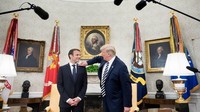 Secara tak diduga, Trump melakukan gerakan membersihkan ketombe dari jas Macron. Momen ini terjadi di depan kerumunan wartawan yang akan mengabadikan foto keduanya. Foto: AFP PHOTO/Brendan Smialowski
