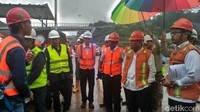 Meski hujan, Basuki tetap mengecek proyek tersebut. Dia dipayungi oleh petugas.