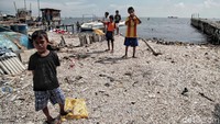 Anak-anak pesisir bermain di pantai yang penuh sampah.