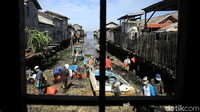 Warga memunguti sampah di pesisir pantai untuk dibuang.