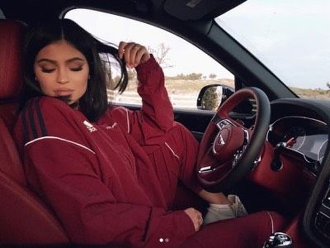 Kali ini Kylie Jenner memakai tracksuit Adidas berwarna merah marun yang matching dengan interior dalam mobil Bentley miliknya. Foto: Istimewa