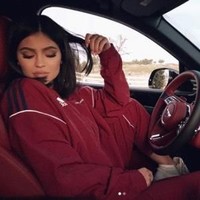 Kali ini Kylie Jenner memakai tracksuit Adidas berwarna merah marun yang matching dengan interior dalam mobil Bentley miliknya. Foto: Istimewa