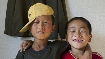 Dua anak laki-laki berpose di depan seragam militer. (Foto: Eric Lafforgue)