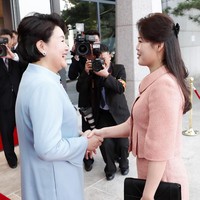 Ri Sol-Ju memilih two-piece dress berwarna peach. Atasannya dipercantik dengan kerah bundar berhiaskan satu kancing sebagai aksen. Foto: Dok. Getty Images