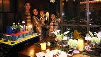Dengan hiasan lampu berwarna kuning kecokelatan, Aliya dan keluarga kecilnya berfoto dengan kue berukuran besar. Foto: Instagram @ruby_26