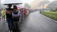 Menggunakan payung dan mantel  warga yang telah melakukan perekaman data KTP Elektronik tetap bertahan dalam antrean  mengurus pencetakan KTP-El di Stand Kementerian Dalam Negeri dalam Acara Nusantara Expo dan Forum 2017 di Teater Keong Mas, Taman Mini Indonesia Indah, saat hujan deras mengguyur kawasan itu, Jakarta, Jumat (20/10). Ribuan warga Jakarta dan sekitarnya rela antre berjam-jam untuk mendapatkan pelayanan ini. Dok. APFI.