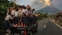 Siswa SMPN 2 Karangasem bersiap berangkat ke sekolah dengan latar Gunung Agung yang menyemburkan abu.