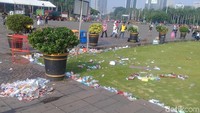 Sampah ada yang masih berserakan di rumput, ada juga yang sudah dikumpulkan di pojokan.