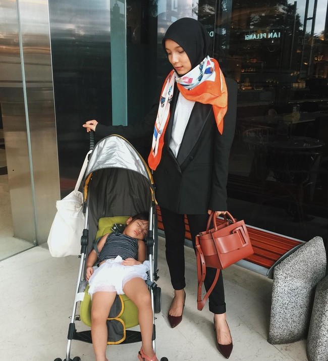 Sematkan scarf motif di leher sebagai syal untuk tampil stylish seketika. Jenahara memadukan scarf satin dengan blazer set bernuansa hitam. Foto: Instagram/JenaharaNasution