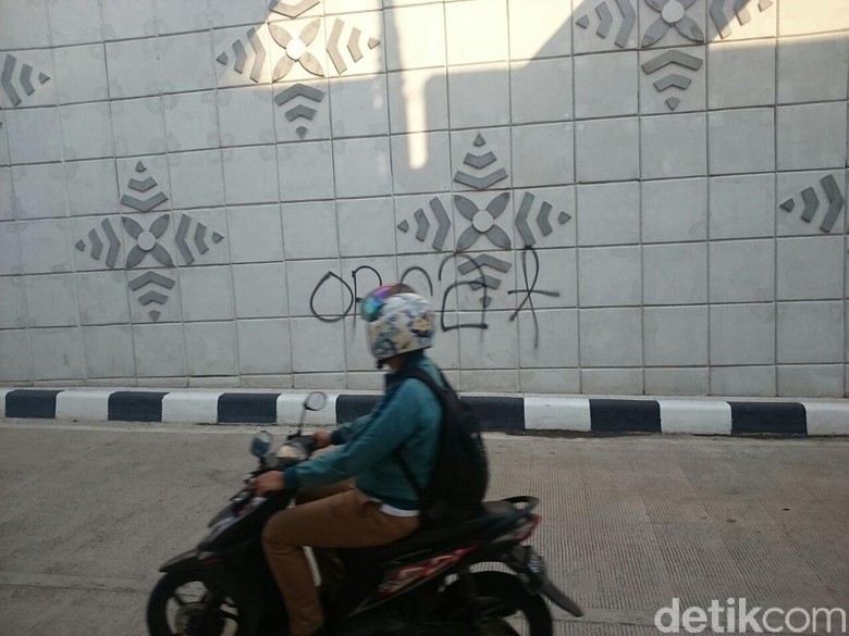 Pengendara motor memperhatikan coretan di dinding underpass Matraman, Senin (30/4/2018) Pengendara motor memperhatikan coretan di dinding underpass Matraman, Senin (30/4/2018)