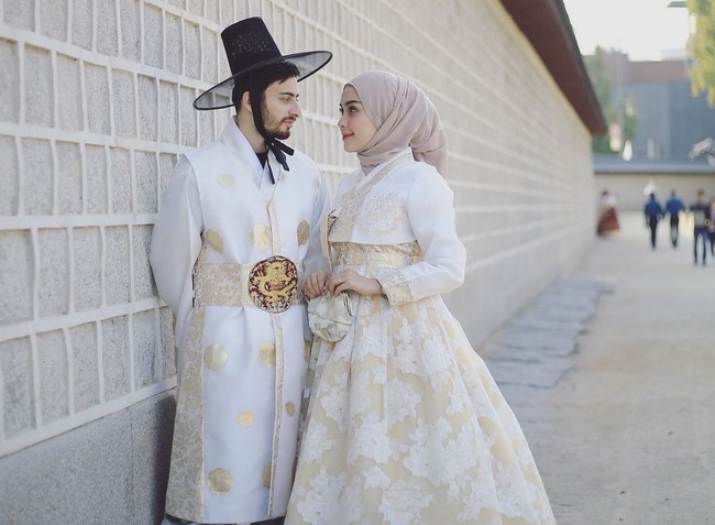 Model berhijab, Hamidah Rachmayanti menghabiskan bulan madu bersama sang suami Irvan Farhad. Mereka tampak kompak memakai busana tradisional Korea berwarna senada. Foto: Instagram