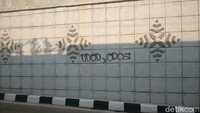 Tangan jahil mencoret dinding underpass dengan cat semprot warna hitam.