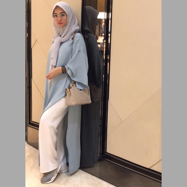 Poppy Bunga kembali memilih atasan berbahan ringan dan jatuh. Ia tampak modis dengan bagian baju oversized dan atasan yang panjangnya hingga mata kaki. Kaca mata yang ia pakai pun tampak modis dan kasual. Foto: Instagram/PoppyBungaRiphat