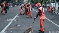 Petugas membersihkan sampah yang berserakan di jalan.