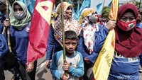 Warga membawa anaknya saat menperingati May Day, Selasa (1/5).