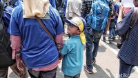 Dengan memakai ikat kepala, seorang anak ikut beraksi.