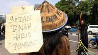 Salah satu poster yang mereka bawa bertuliskan setan tanah harus tumbang