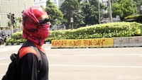 Seorang peserta aksi berjalan di depan tulisan May Day Is Not Fun Day.