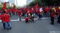 Massa buruh tampak menunggu dengan duduk-duduk di jalan.