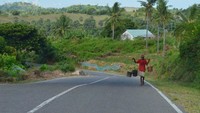 Jalan dengan kontur menanjak di antara bukit dan deretan pohon kelapa. Pool/Kementerian PUPR.