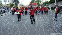 Polisi memasang kawat berduri untuk menghadang massa.