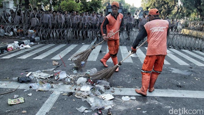 Petugas kebersihan membersihkan sampah di Jalan Medan Merdeka Utara, Jakarta. Sampah ini berserakan usai peringatan May Day, Selasa (1/5).