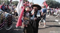Seorang buruh membawa boneka yang dinaikan ke atas sepeda onthel.