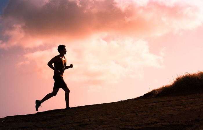 Fitness male running outdoors during sunset. Healthy lifestyle concept.