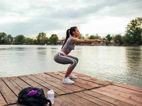 Side view image of fitness woman doing sit ups on an exercise mat. Muscular young woman lying on exercise mat with her hands behind head doing stomach exercises.