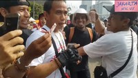 Stedi Repki Watung (37) juga mengalami intimidasi di CFD. Netizen memperhatikan gelang di tangan kanan Stedi. Lalu netizen menyoroti gelang bentuk biji-bijian yang dipakai pria yang mengibaskan uang ke Stedi. (Foto: Screenshot YouTube Jakarta Nicus)