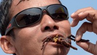 Dengan santainya warga lokal menikmati aping, sebutan tarantula goreng dalam bahasa lokal. Wajahnya sama sekali tidak takut ya? Foto: Reuters
