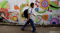 Seorang warga melintas diantara seni mural bergambar bunga warna-warni di kawasan Pejaten, Jakarta Selatan, Kamis (3/5/2018).