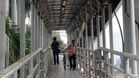 Seorang warga menuntun sepda melintasi JPO.