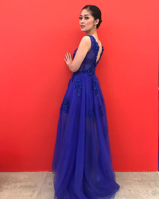 Berpose di dinding merah, wanita 28 tahun tersebut mengenakan gaun biru tua nan kontras dari ExmeCouture. Foto: Instagram Gracia Indri