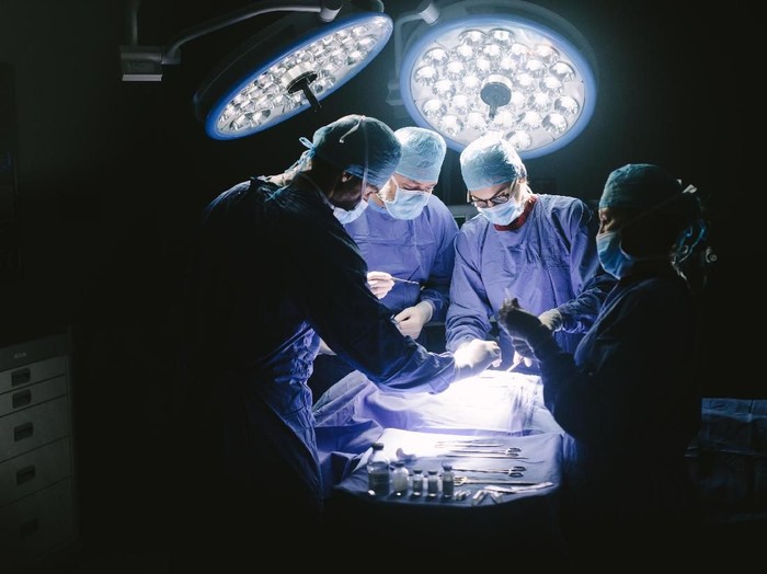 Doctors during surgery on patient in hospital. Surgeons team working at the hospital performing surgical procedure in operating theatre.