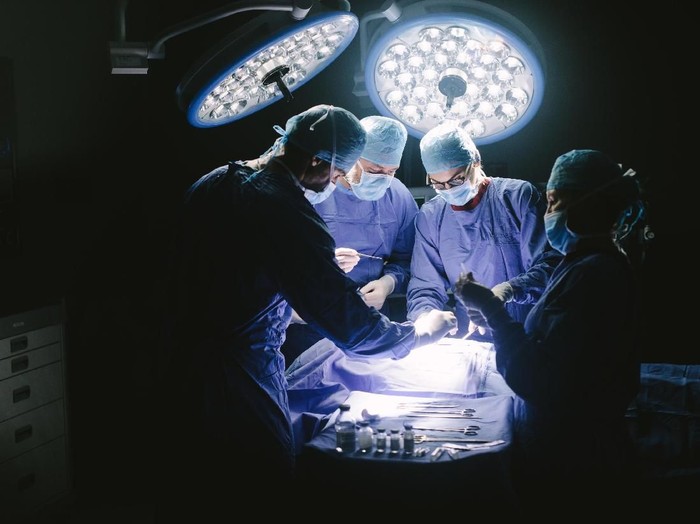 ilustrasi operasi ganti kelamin Doctors during surgery on patient in hospital. Surgeons team working at the hospital performing surgical procedure in operating theatre.