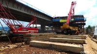 Pekerja tampak melakukan pekerjaan seperti mengangkat kayu dan mengelas besi. Ada pula pekerja yang tampak sibuk di bagian atap tiang, dari jalur yang sudah mulai terhubung.