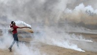 Ia berusaha mengembalikan gas air mata yang ditembakan tentara Israel. REUTERS/Ibraheem Abu Mustafa.