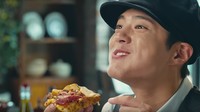Kayaknya enak banget nih. Park Bo Gum terlihat sedang menikmati sepotong pizza dengan aneka topping gurih. Nyam! Foto: Istimewa