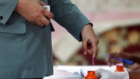 Sebagai tanda telah melaksanakan Pemilu anggota kepolisian memasukkan jari kelingkingnya ke tinta berwarna ungu yang telah disediakan. Lai Seng Sin/Reuters.