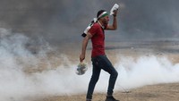 Seorang warga menyiramkan air ke matanya yang terkena gas air mata. REUTERS/Ibraheem Abu Mustafa.