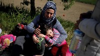 Seorang imigran cilik bernama Zena terlihat beristirahat dipangkuan sang ibu, Zamilla Ammal setelah kelelahan menyusuri sungai Evros yang memisahkan Turki dengan Yunani. Alkis Konstantinidis/Reuters.