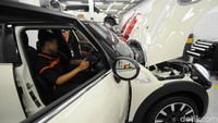 Para teknisi dengan teliti melakukan perawatan dan perbaikan mobil Mini Cooper.