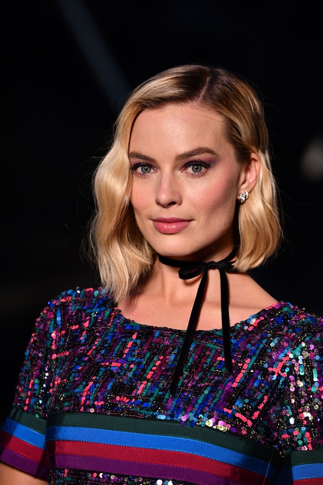 Sedikit sentuhan 90an pada gayanya. Choker hitam beraksen pita mempermanis penampilan Margot. Foto: Pascal Le Segretain/Getty Images for Chanel
