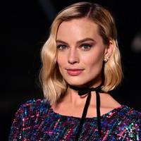 Sedikit sentuhan 90an pada gayanya. Choker hitam beraksen pita mempermanis penampilan Margot. Foto: Pascal Le Segretain/Getty Images for Chanel