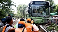 Sejumlah Petugas Penanganan Sarana dan Prasarana Umum (PPSU) bergotong-royong mengevakuasi bus TransJ usai seruduk pembatas jalan di Simprug, Kebayoran Lama, Jakarta, Senin (7/5/2018).
